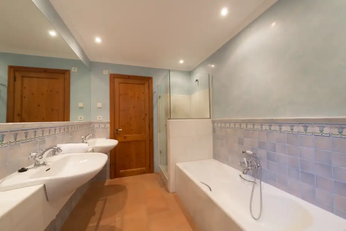 A tiled bathroom with a bathtub, shower, and sink.