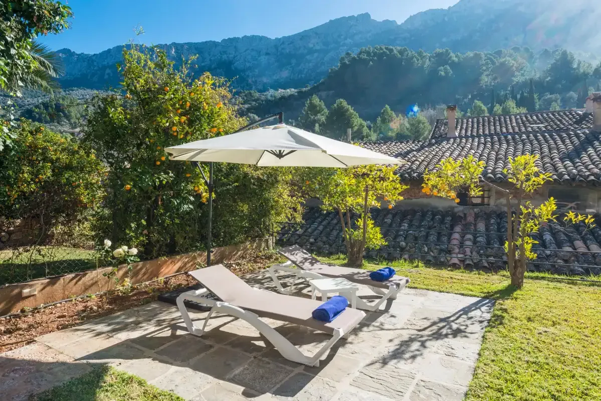 A sunlit outdoor patio with lounge seating and mountain views.