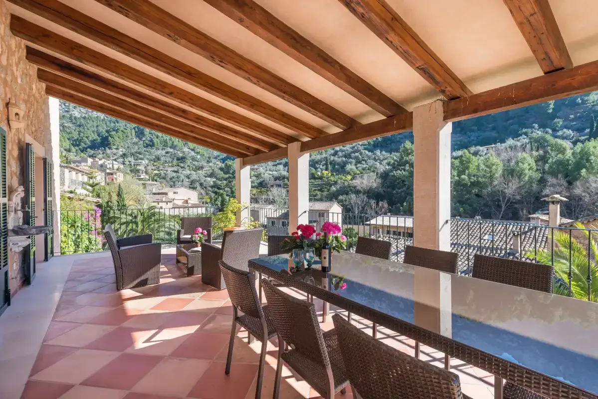 A covered outdoor dining area with a long table and mountain views.