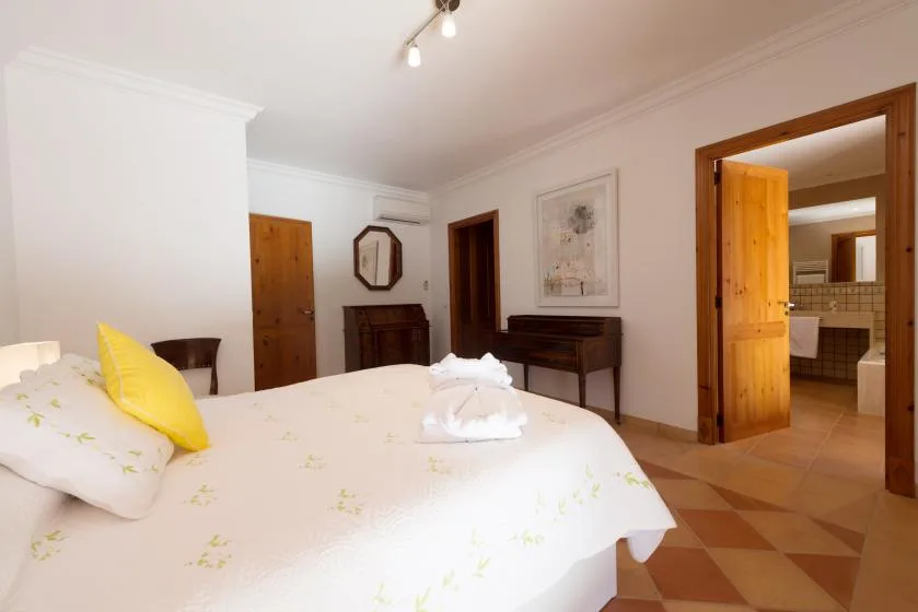 A bedroom with a bed and an open doorway leading to a tiled bathroom.