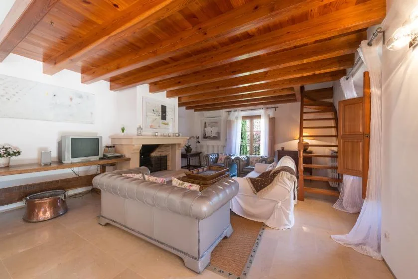 A living room with seating, a fireplace, and exposed wooden ceiling beams.