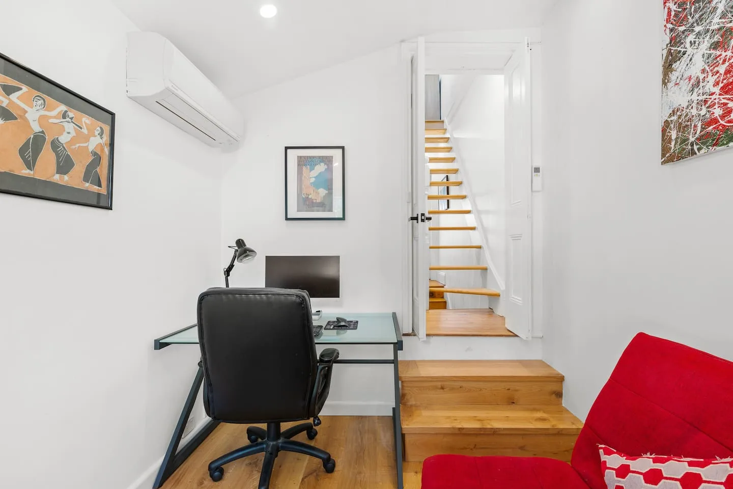 Un pequeño espacio de trabajo tiene un escritorio y una silla junto a una escalera.