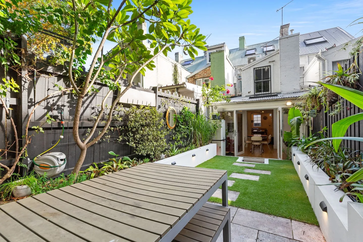 A landscaped courtyard with a wooden table and a small lawn beside the house.