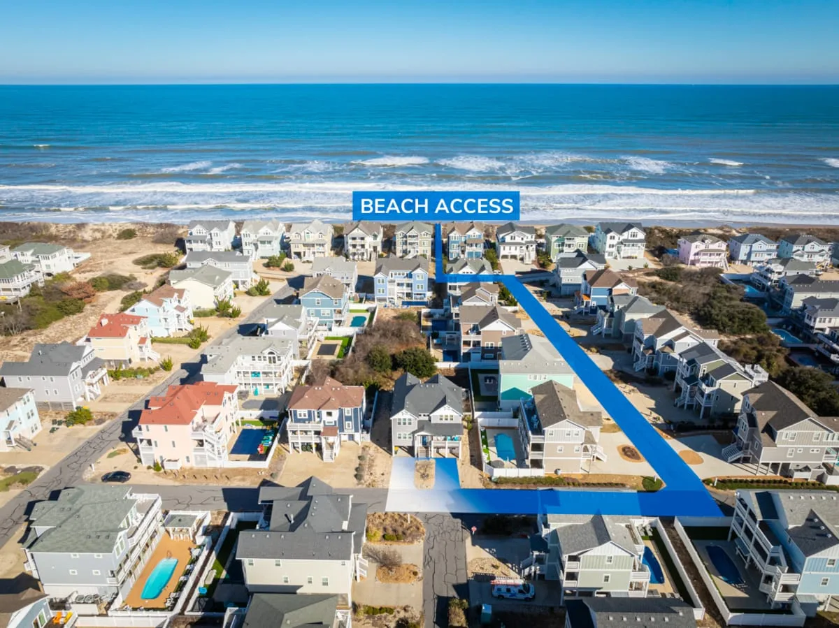Aerial view of coastal homes beside the ocean, with a marked beach access route.