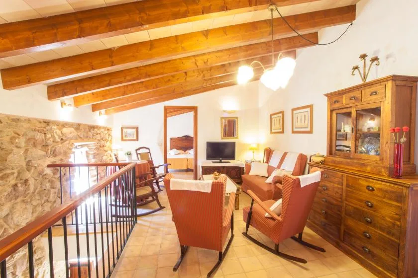 A living room with seating arranged around a television beneath exposed wooden ceiling beams.