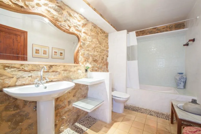 A bathroom with a sink, toilet, and bathtub beside tiled walls.