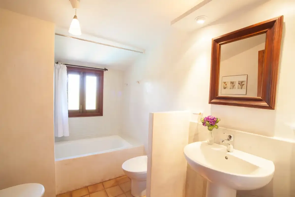 A bathroom with a bathtub, toilet, and wall-mounted sink.