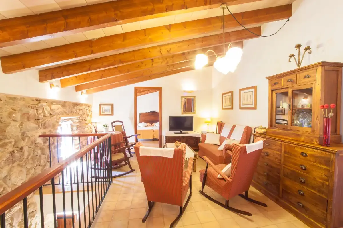 A living room with seating, a television, and exposed wooden ceiling beams.