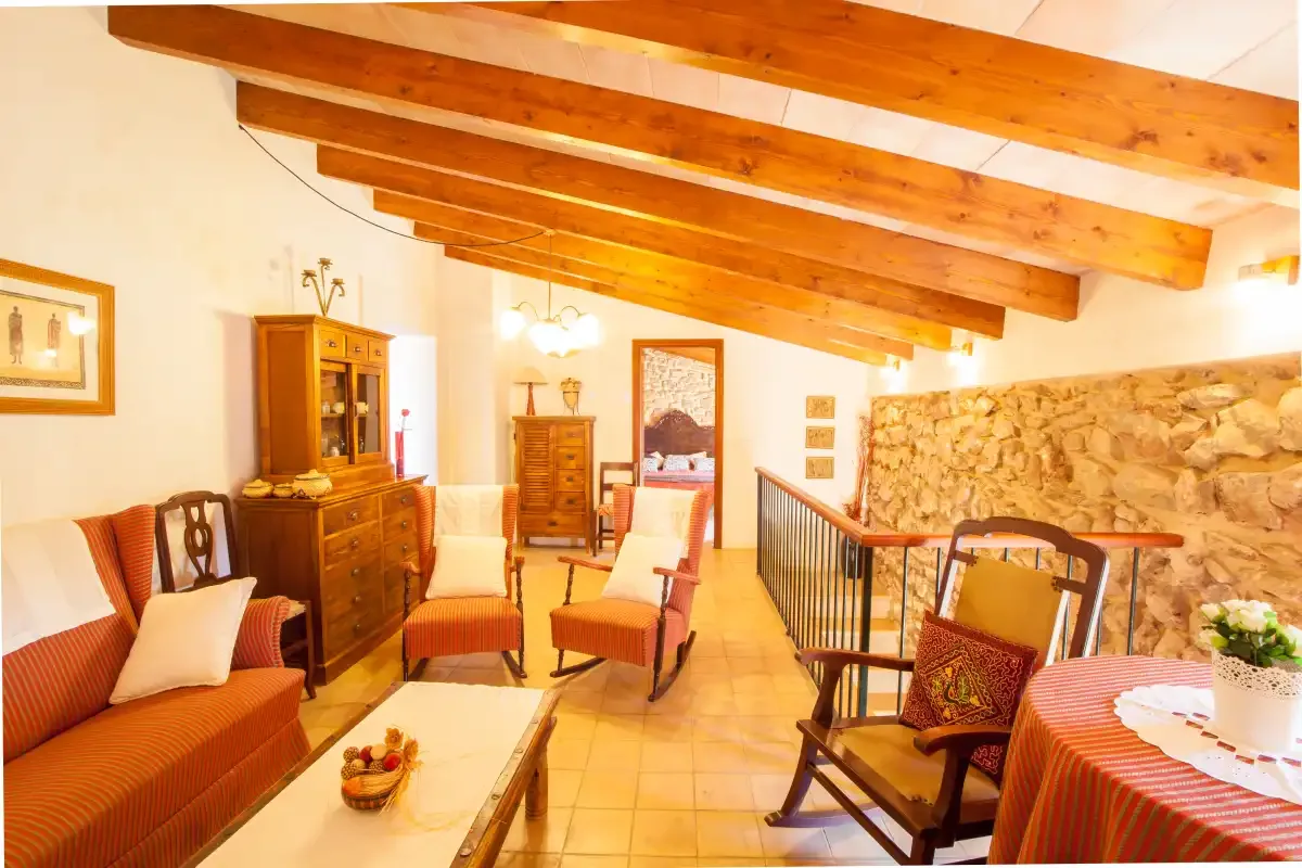 A warm interior living area with seating, wooden beams, and a stone wall.