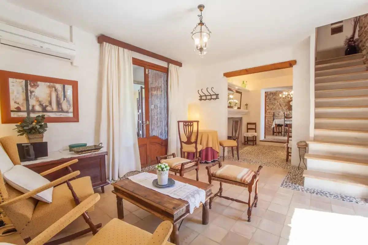 A bright living and dining area with seating, a wooden table, and an open doorway.