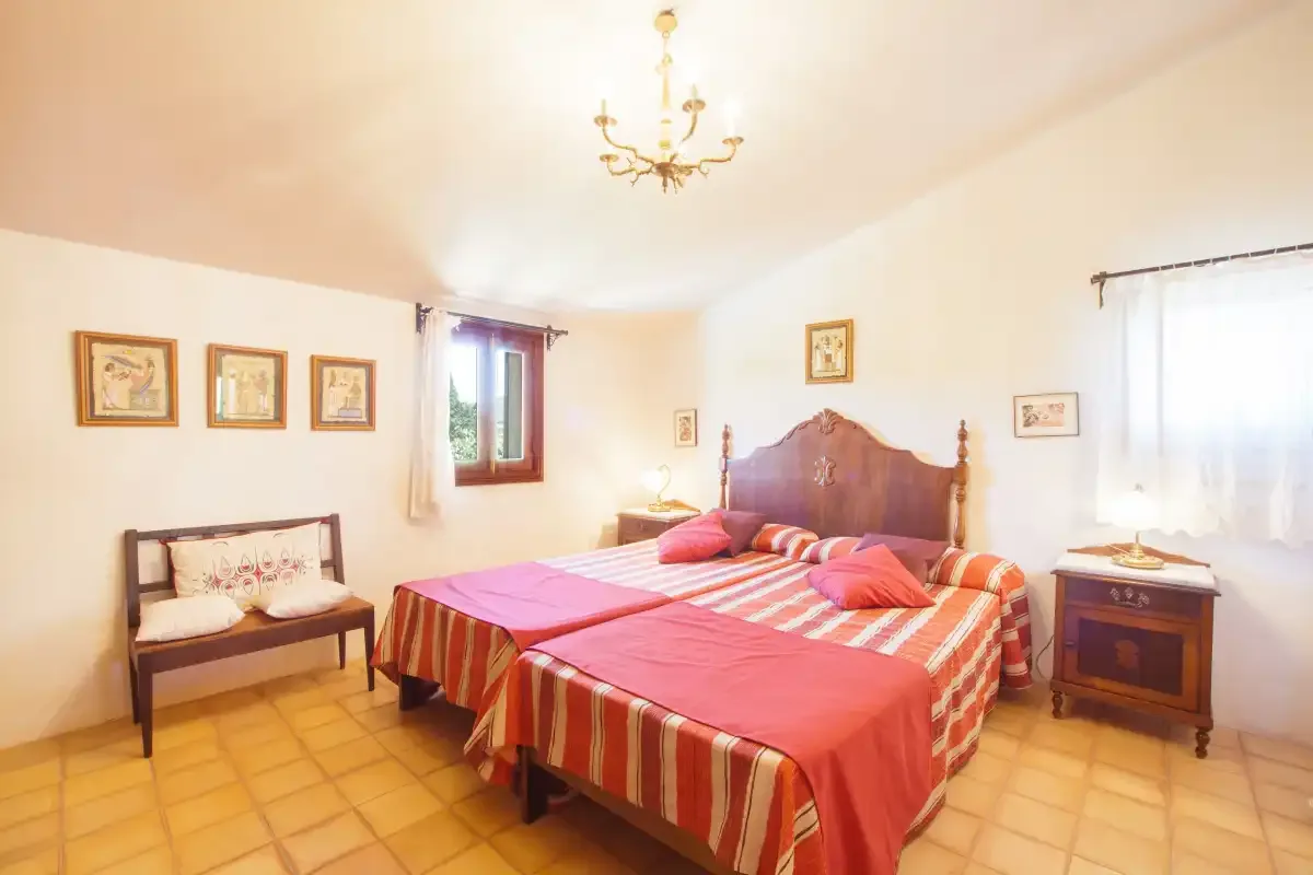 A bedroom with a large bed, a bench, and bedside tables.