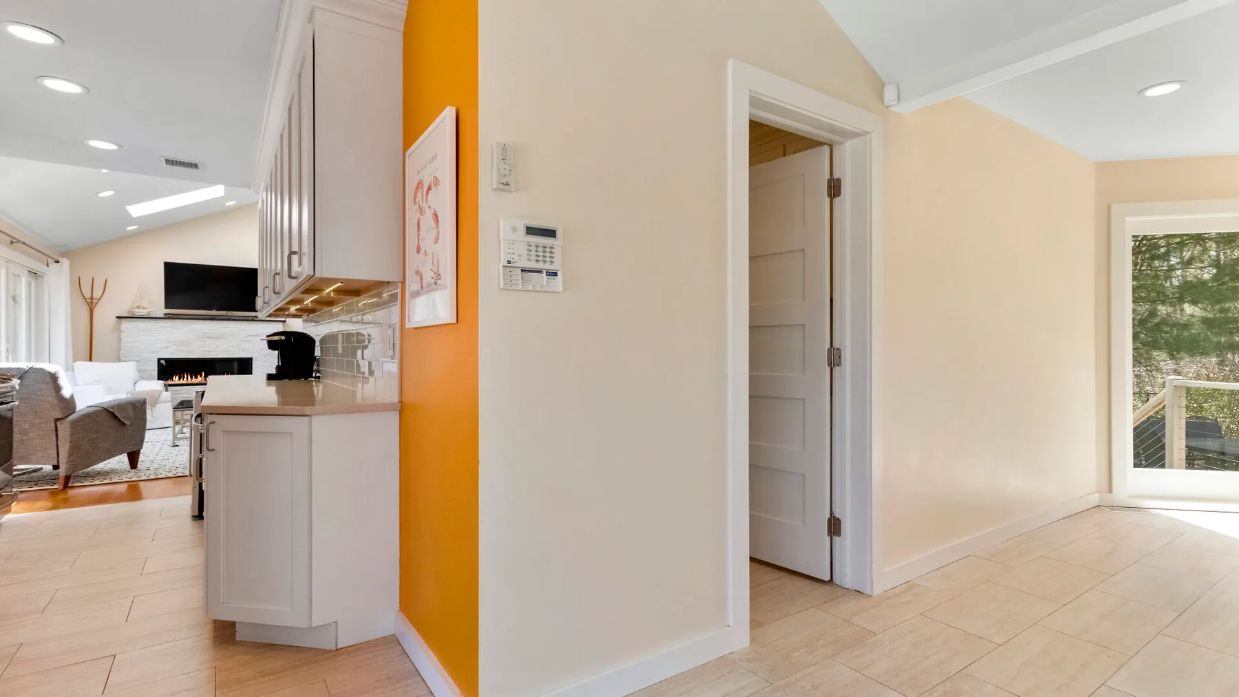 Una sala de estar y cocina de concepto abierto, con una puerta y suelo de baldosas claras.