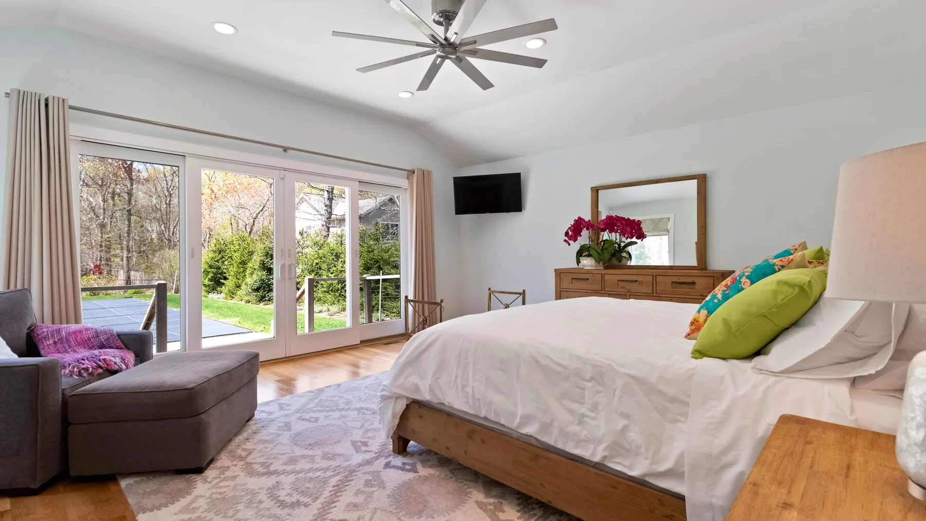 Un dormitorio luminoso con una cama grande y puertas de cristal que dan al jardín.