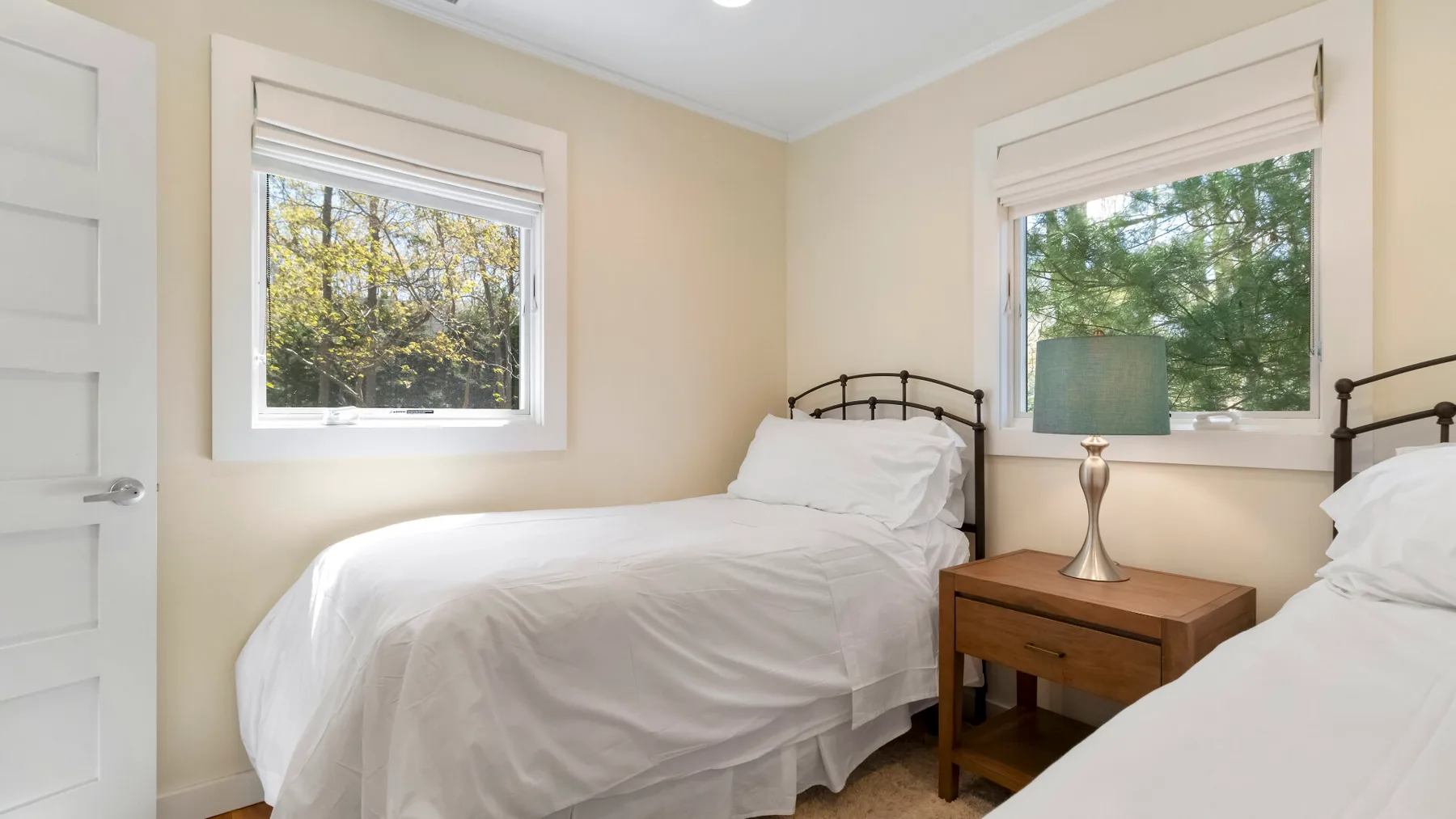 Un dormitorio con dos camas y una mesita de madera entre ellas.