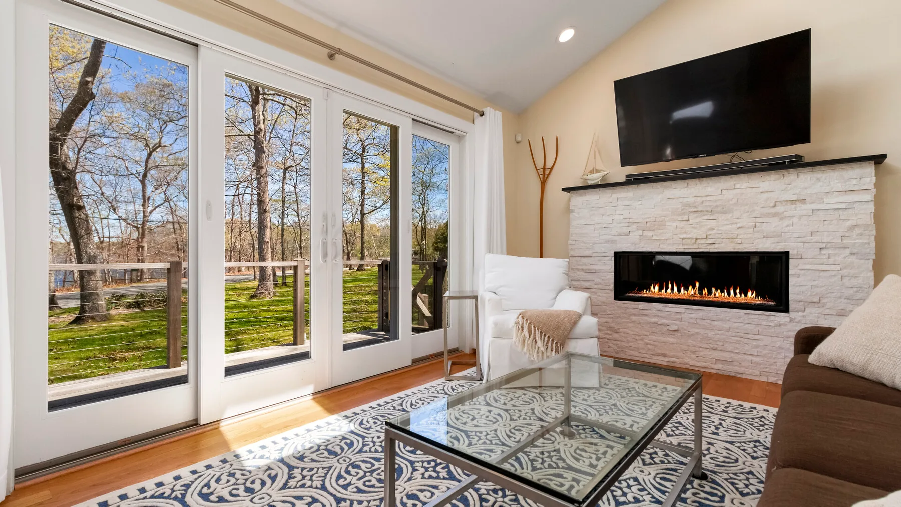Una sala luminosa con grandes ventanas, una chimenea y una mesa de centro de vidrio.