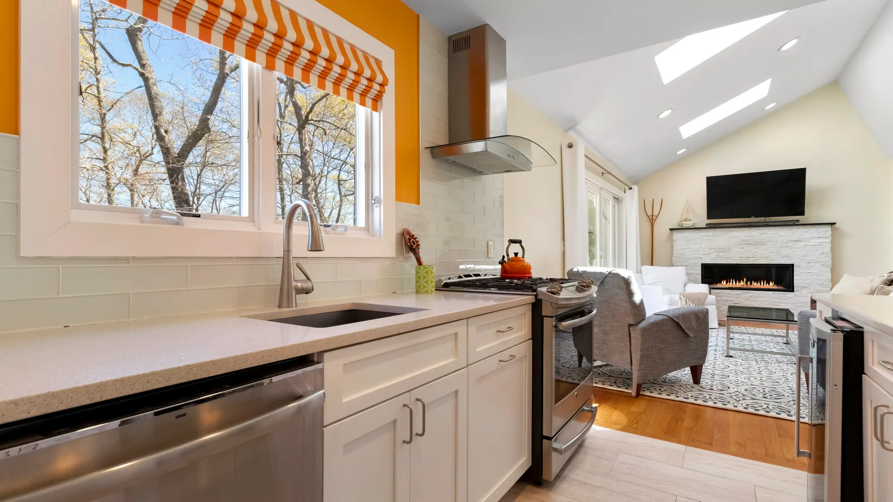 Una cocina luminosa se abre a una sala de estar con chimenea y televisor.