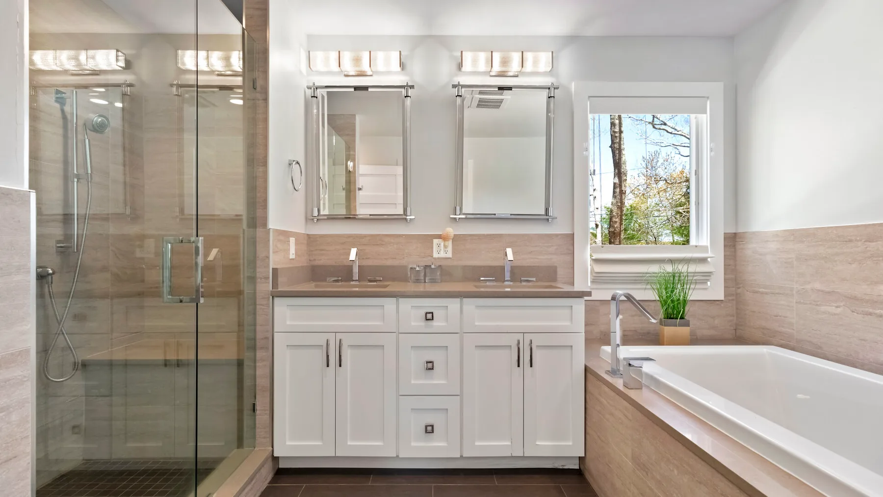 Un baño luminoso con ducha de vidrio, lavabo doble y bañera.