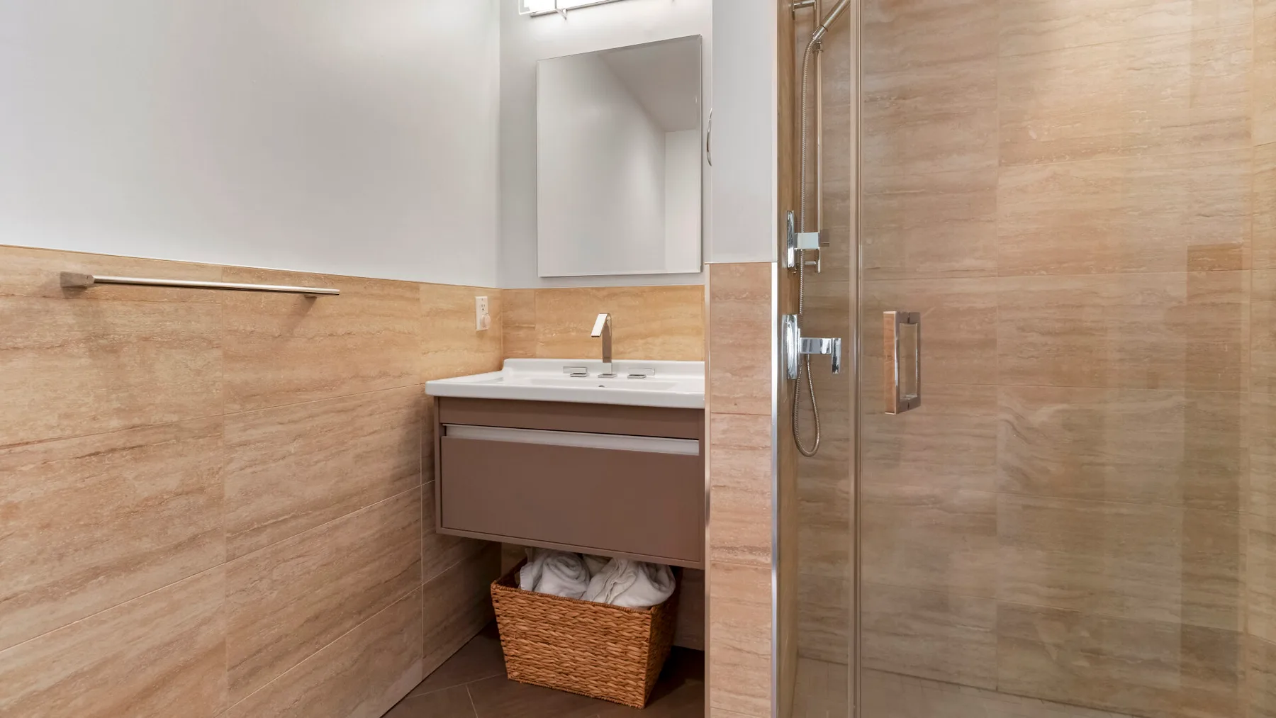 Un tocador de baño con espejo está junto a una ducha con azulejos.