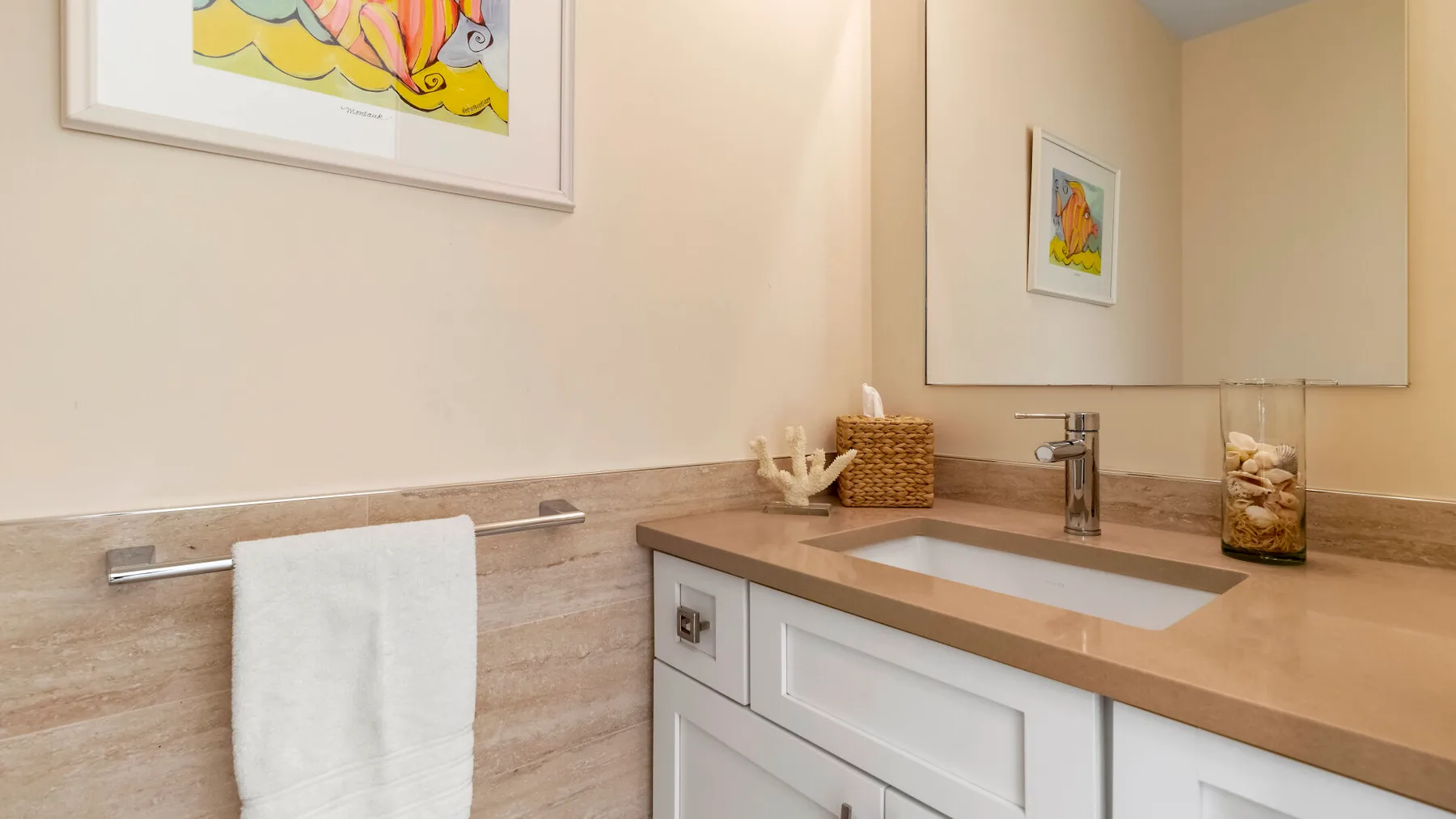 Un tocador de baño con lavabo, espejo y toalla blanca.