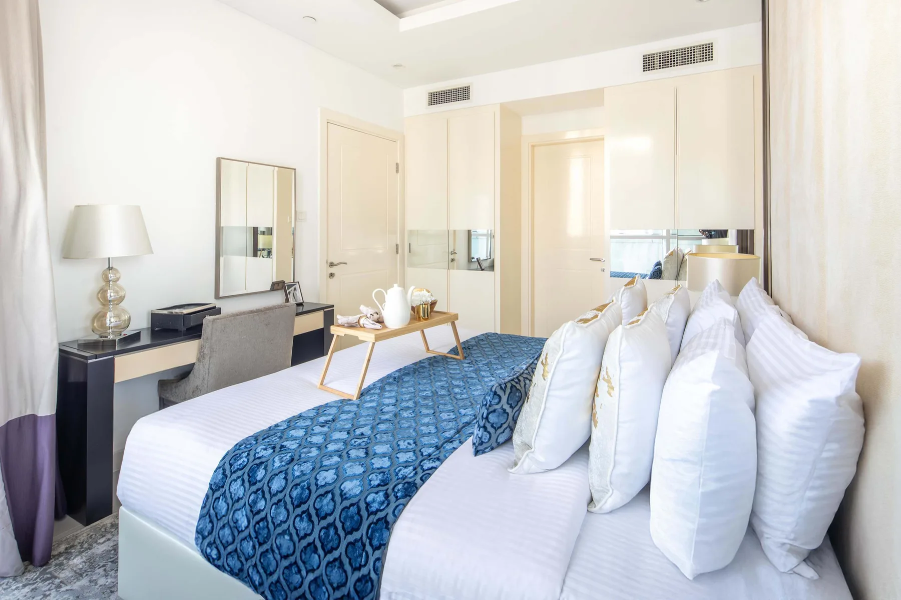 A bright bedroom with a bed covered in blue patterned bedding.