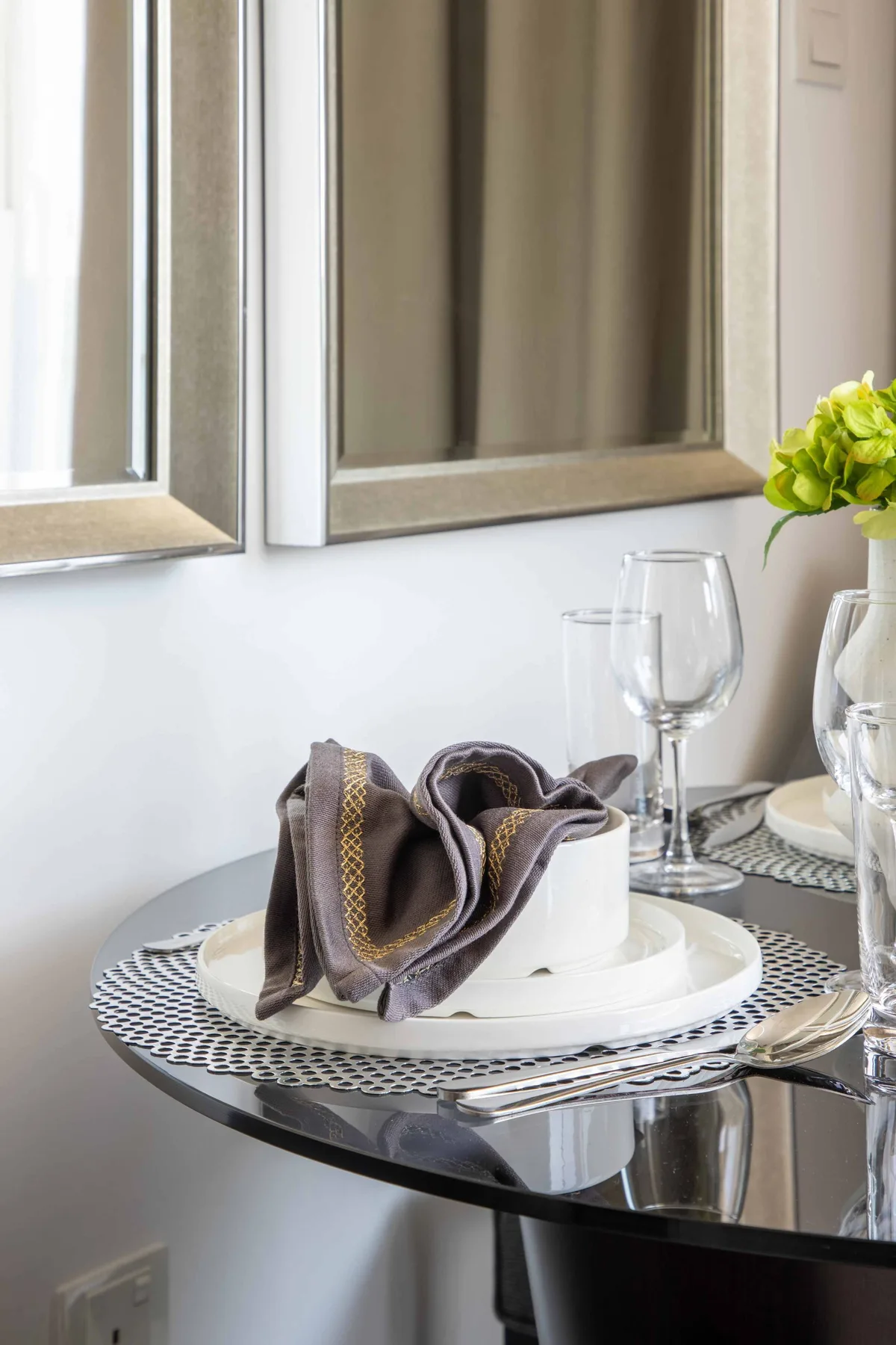 A dining table is set with plates, folded napkins, and wine glasses.