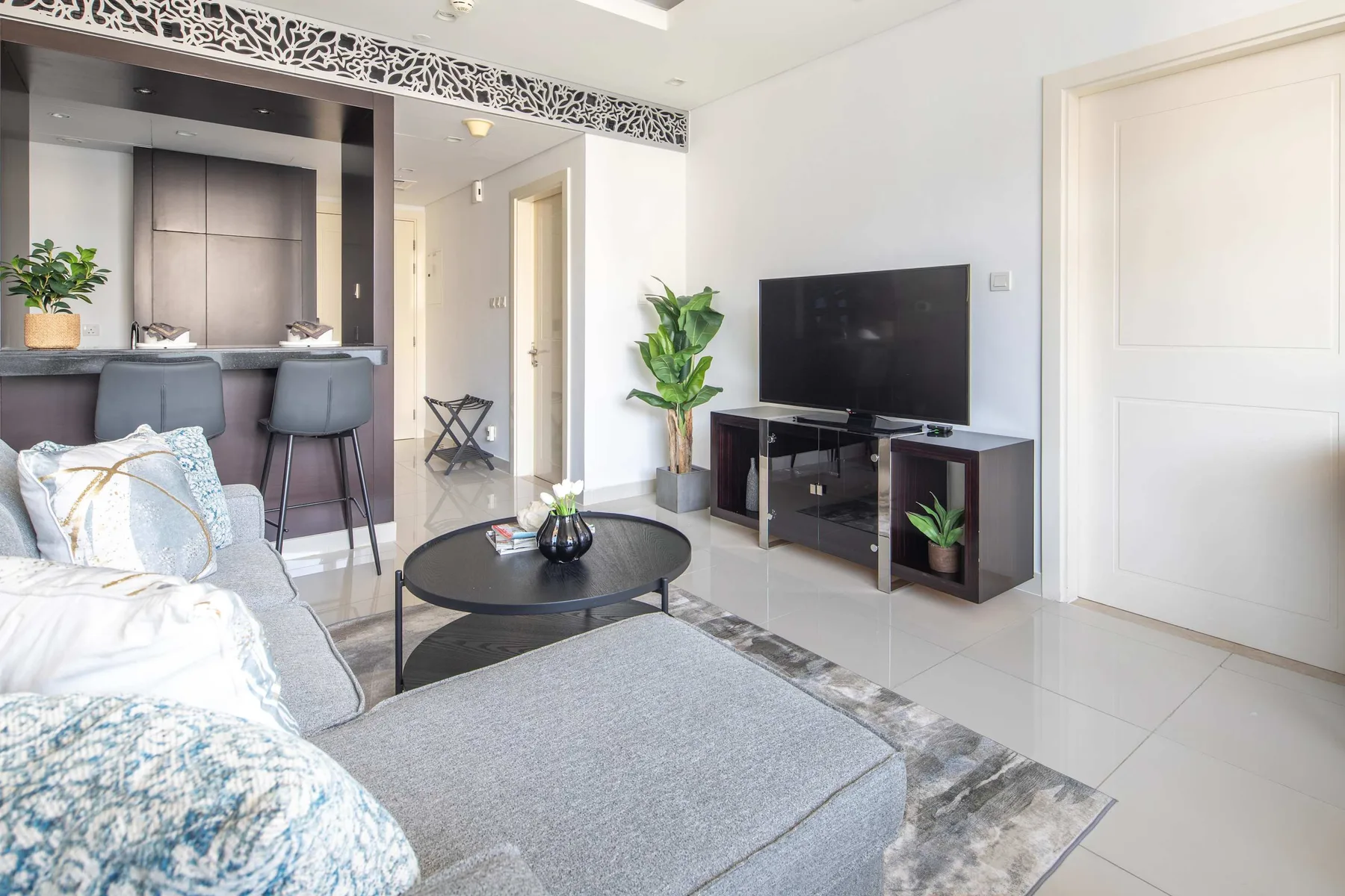 A bright living room with a television, seating, and a small dining counter.