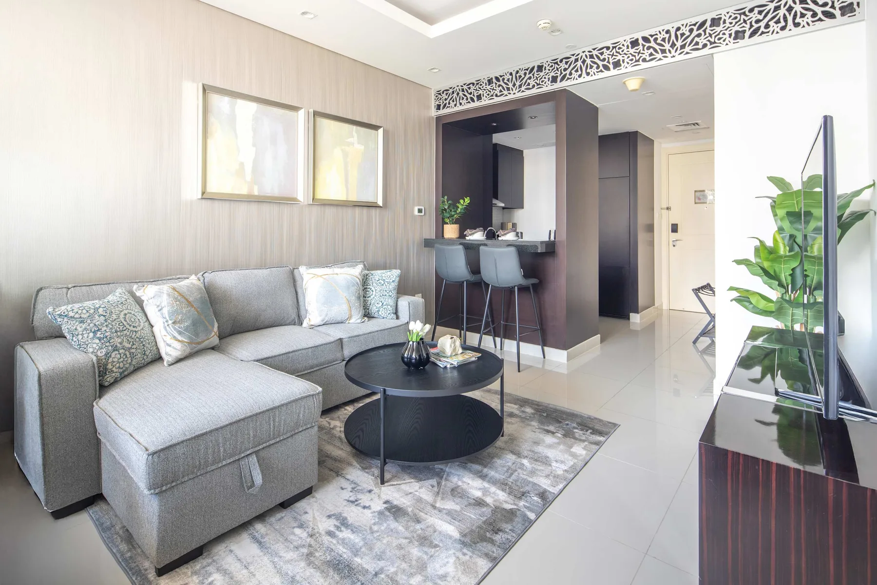 A bright living room with sectional seating, a coffee table, and an open kitchen.