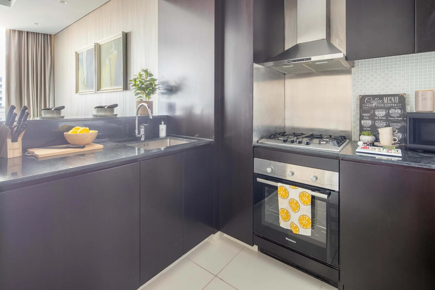 A modern kitchen with dark cabinets, a stovetop, and an oven.