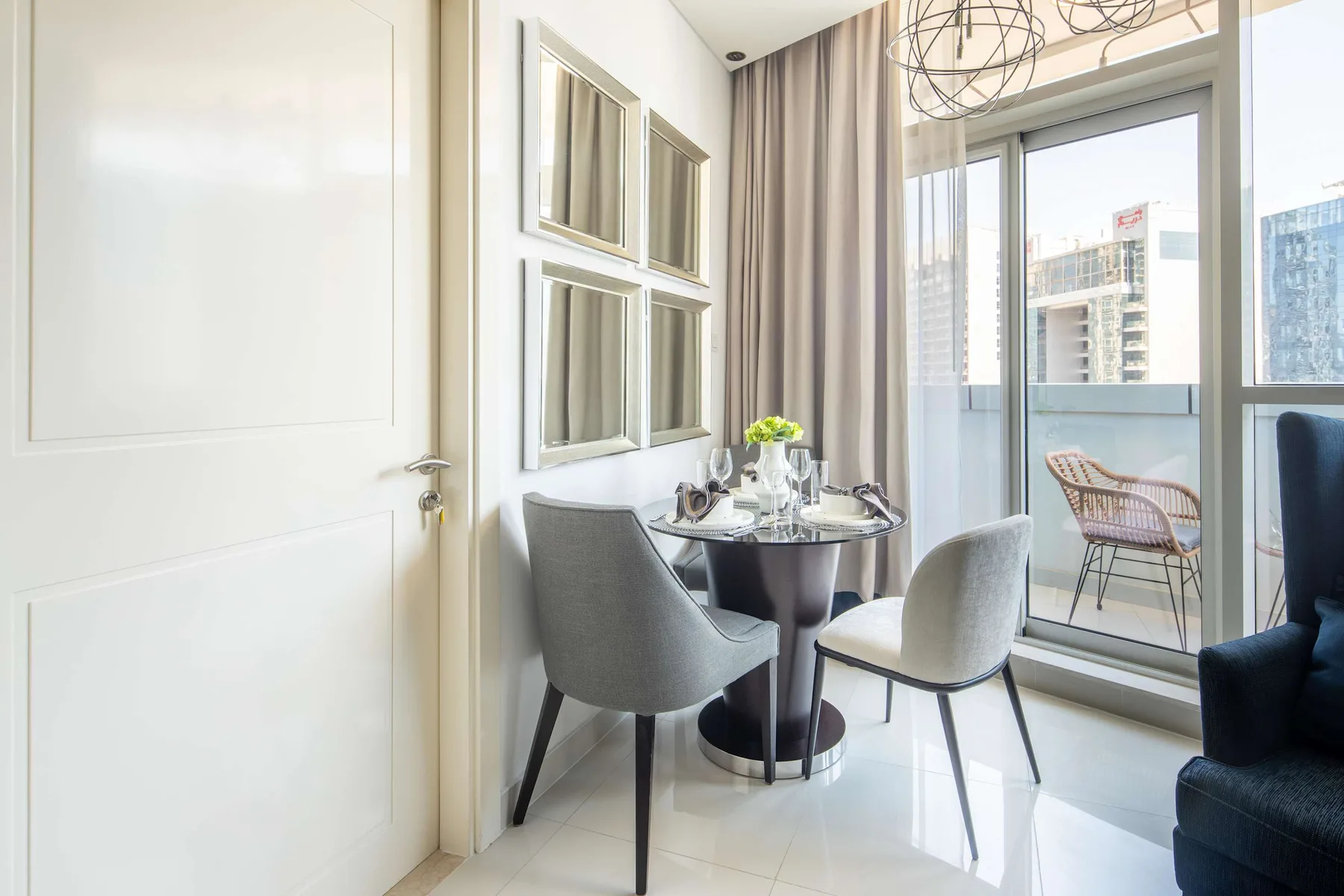 A bright dining area with a round table beside floor-to-ceiling windows.