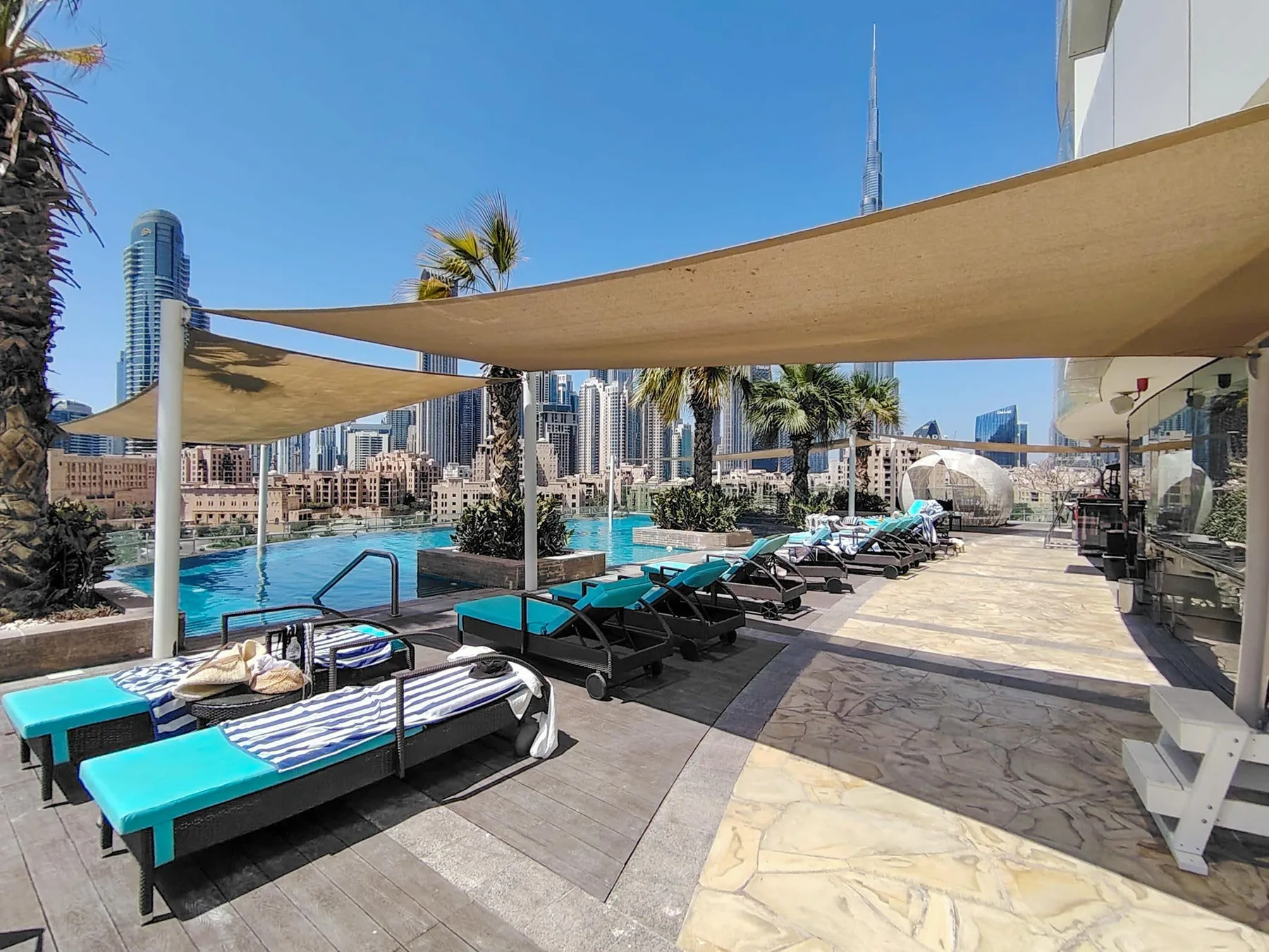 A rooftop pool deck with lounge seating and shade canopies overlooks the surrounding skyline.