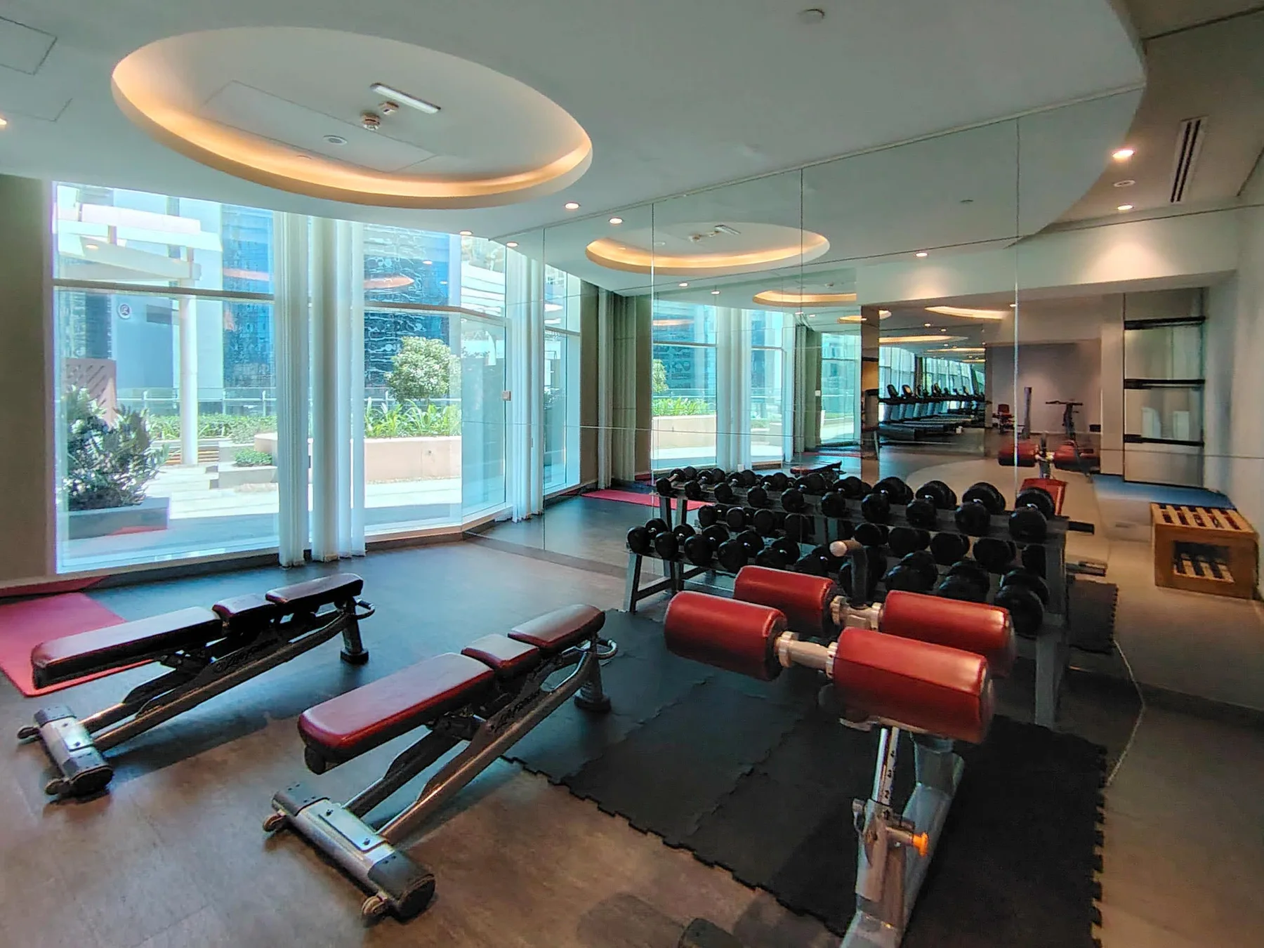 A gym with weight machines and large windows overlooking the outdoors.