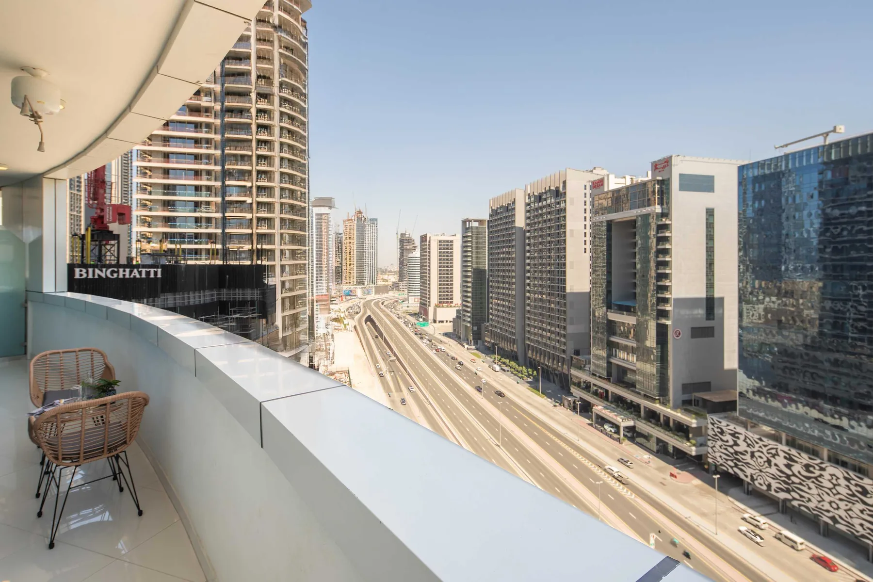 Un balcón da a una amplia vía y a edificios modernos de gran altura.