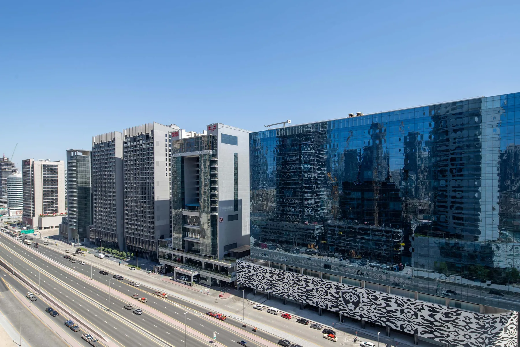 A row of modern office buildings stands beside a busy multi-lane road.