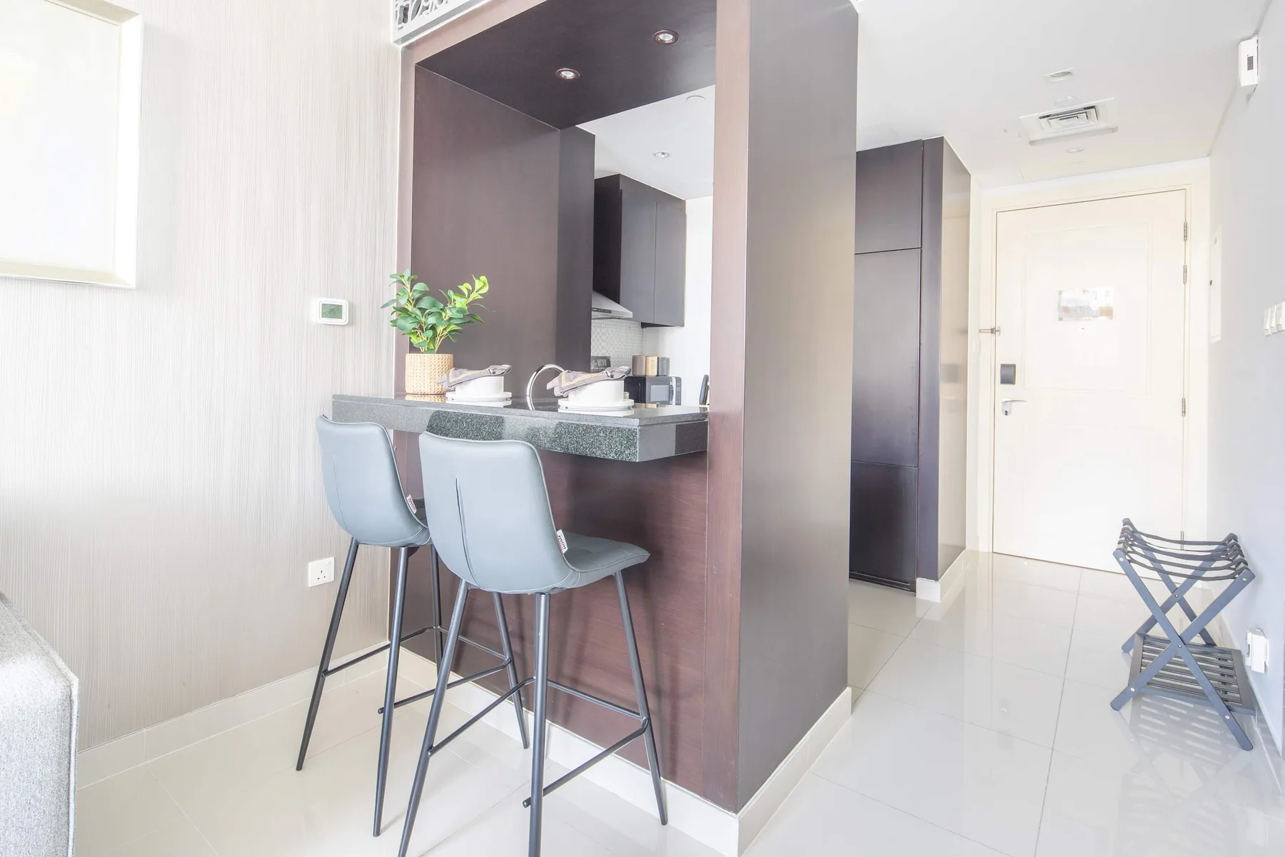 A compact kitchenette with counter seating opens onto a bright entryway.