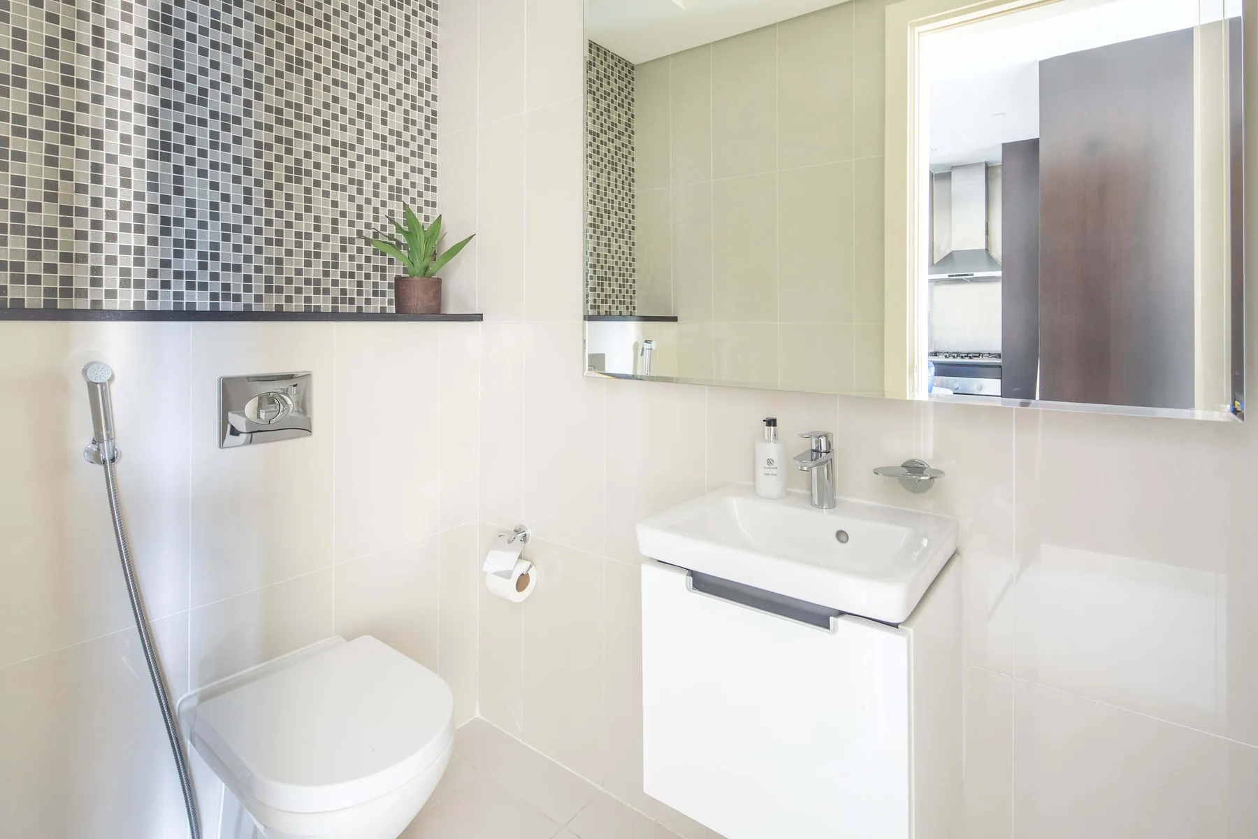 A bright bathroom with a wall-mounted sink, toilet, and large mirror.