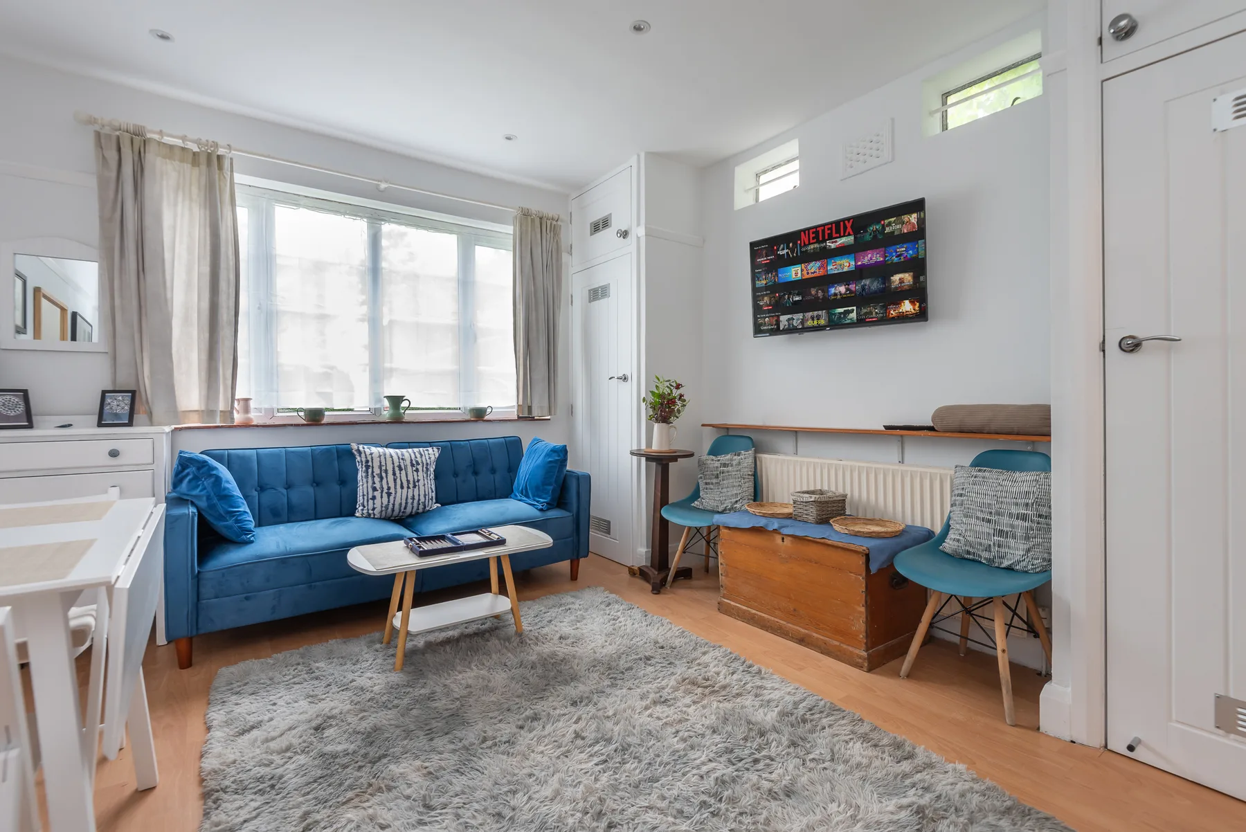 A bright living room with blue seating and a wall-mounted television.