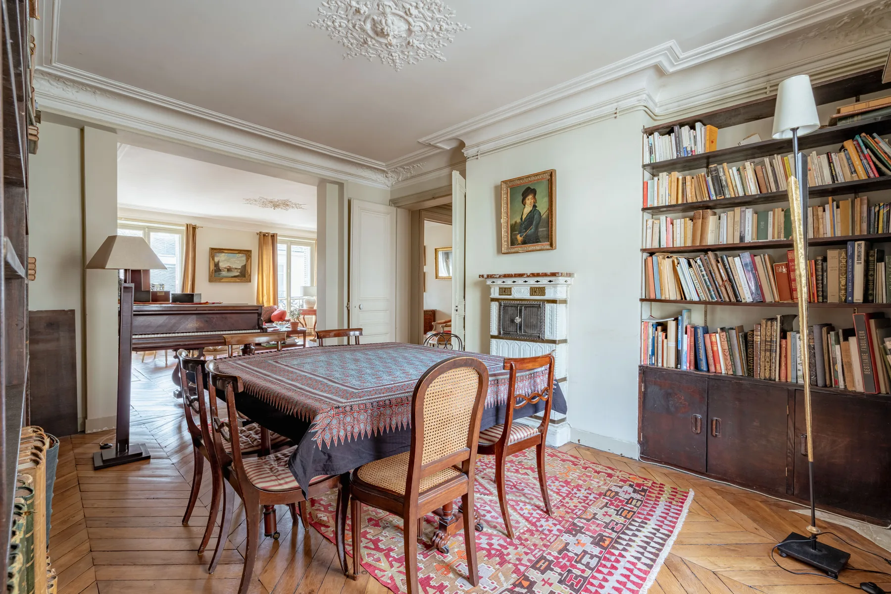 A dining room with a long table, chairs, and bookshelves along the wall.