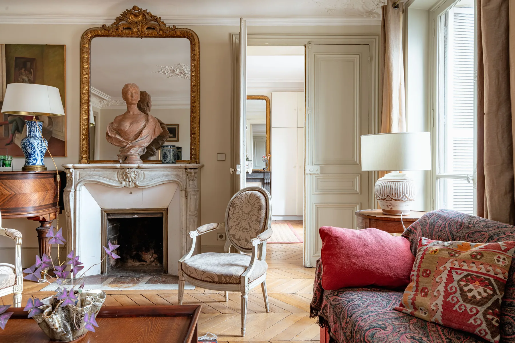 A sitting room with a fireplace, ornate mirror, and seating.