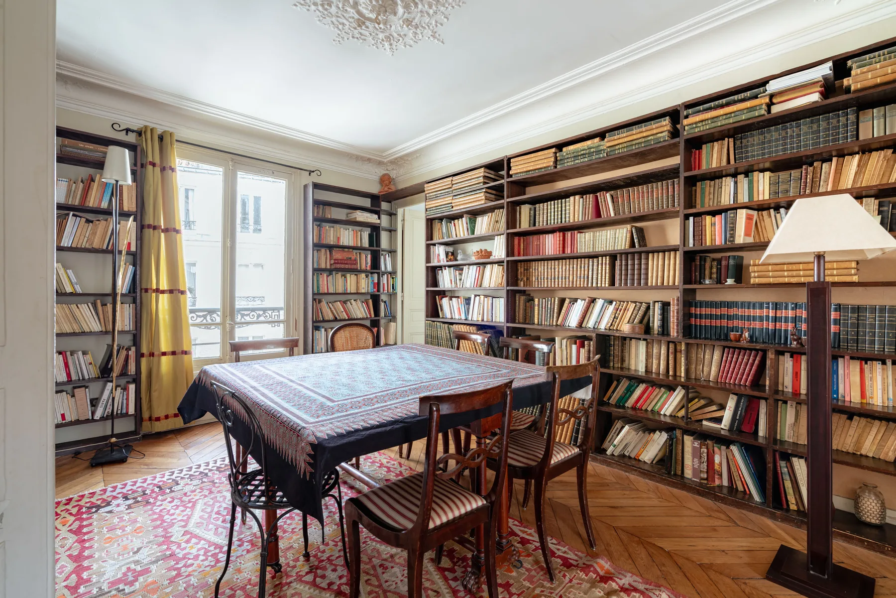 A book-lined room with a large table and chairs.