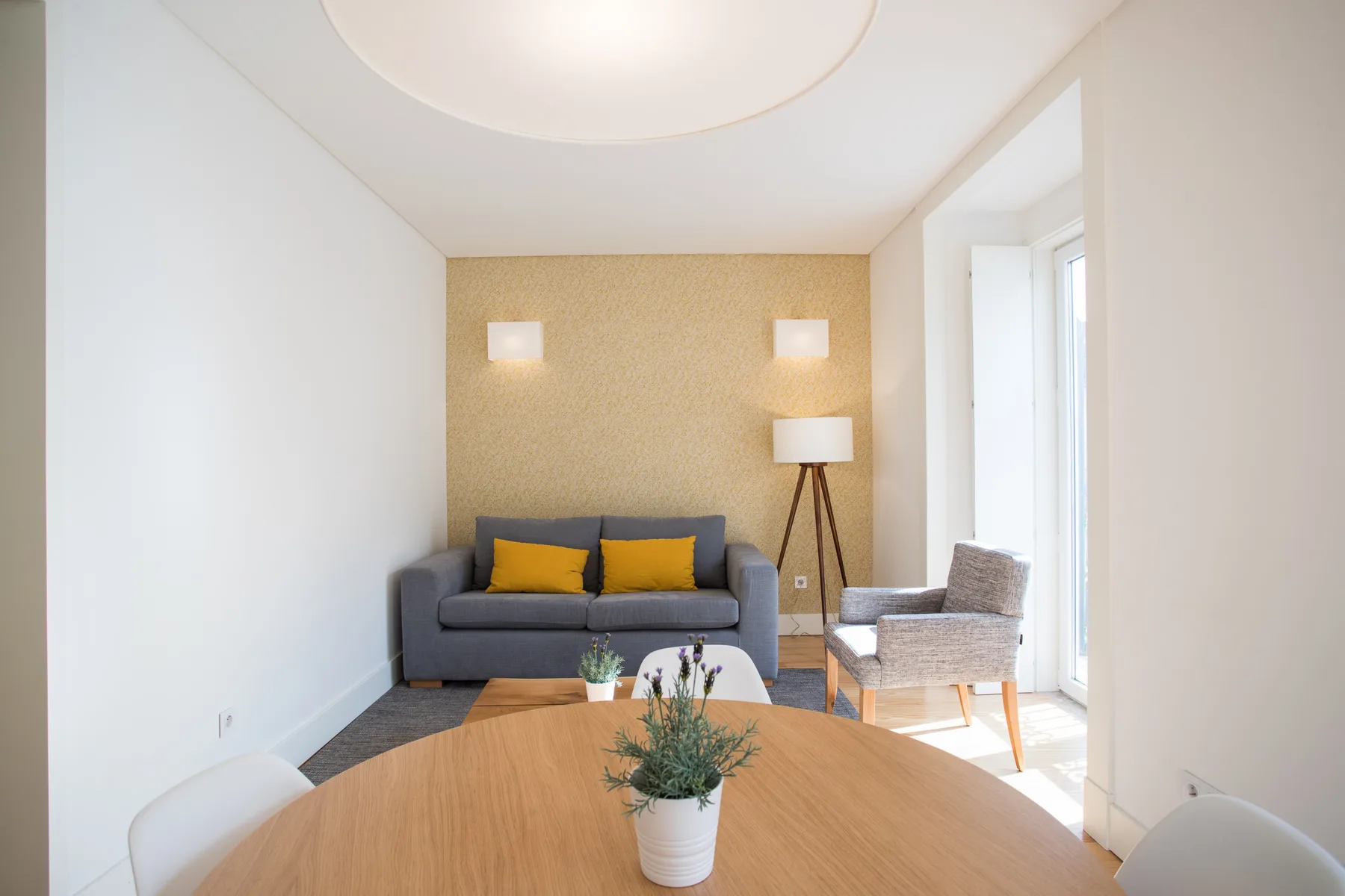 A bright living and dining area with seating arranged around a wooden table.