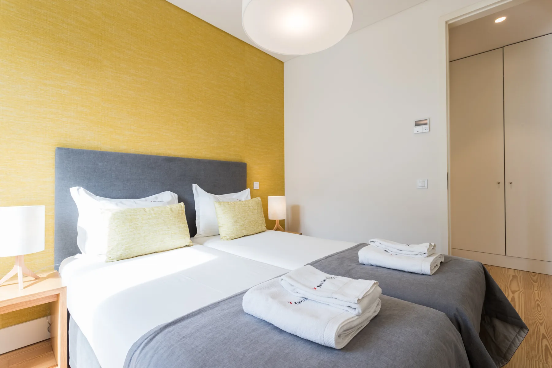 A bedroom with two beds, white bedding, and folded towels.