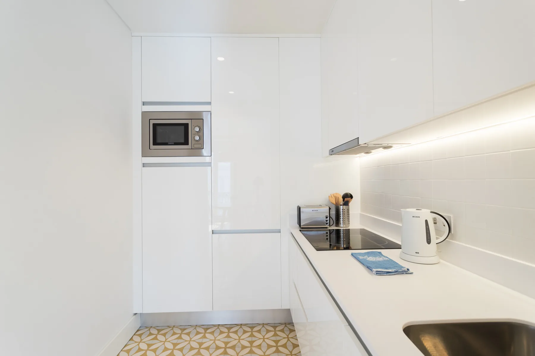A bright modern kitchen with a built-in microwave and a long countertop.