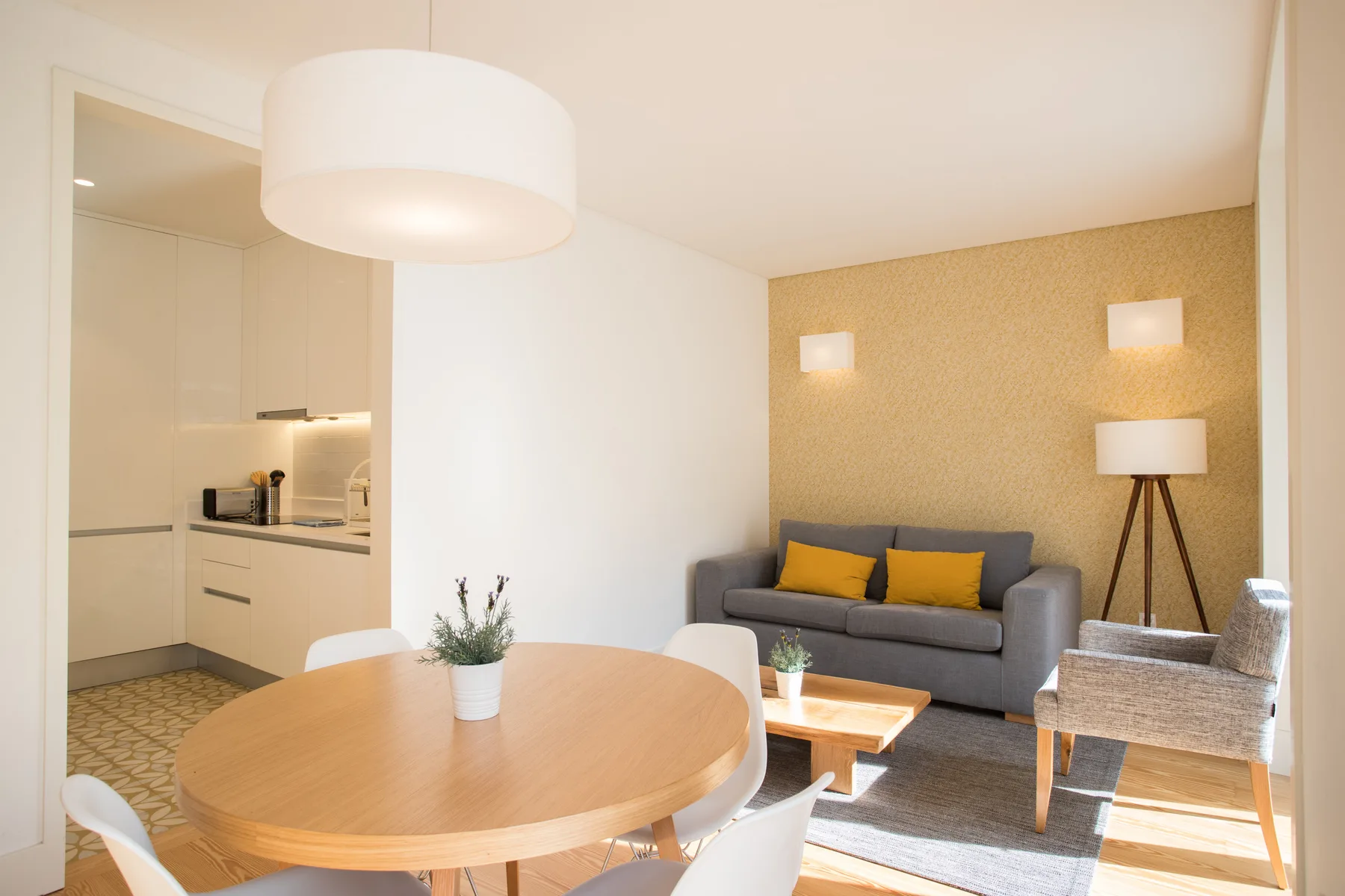 A living and dining area with a gray sofa and a round wooden table.