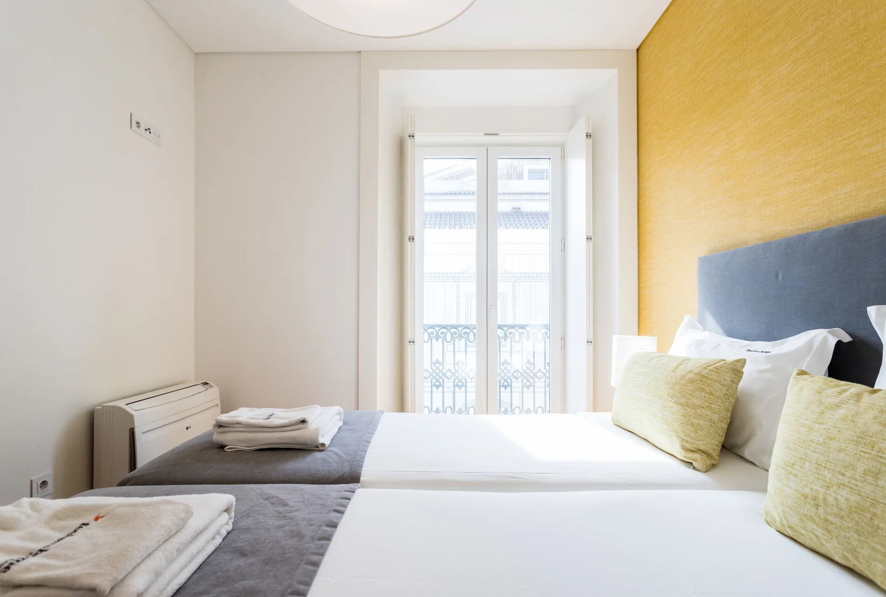A bedroom with two beds and a bright window.