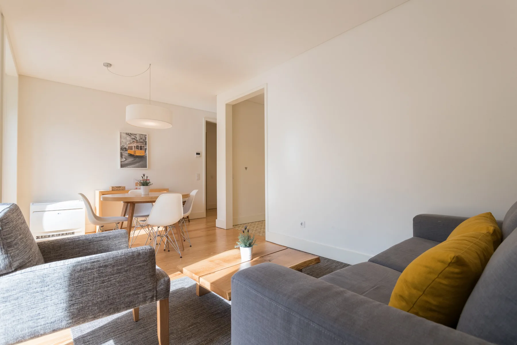 Bright living and dining area with gray seating and a wooden table.