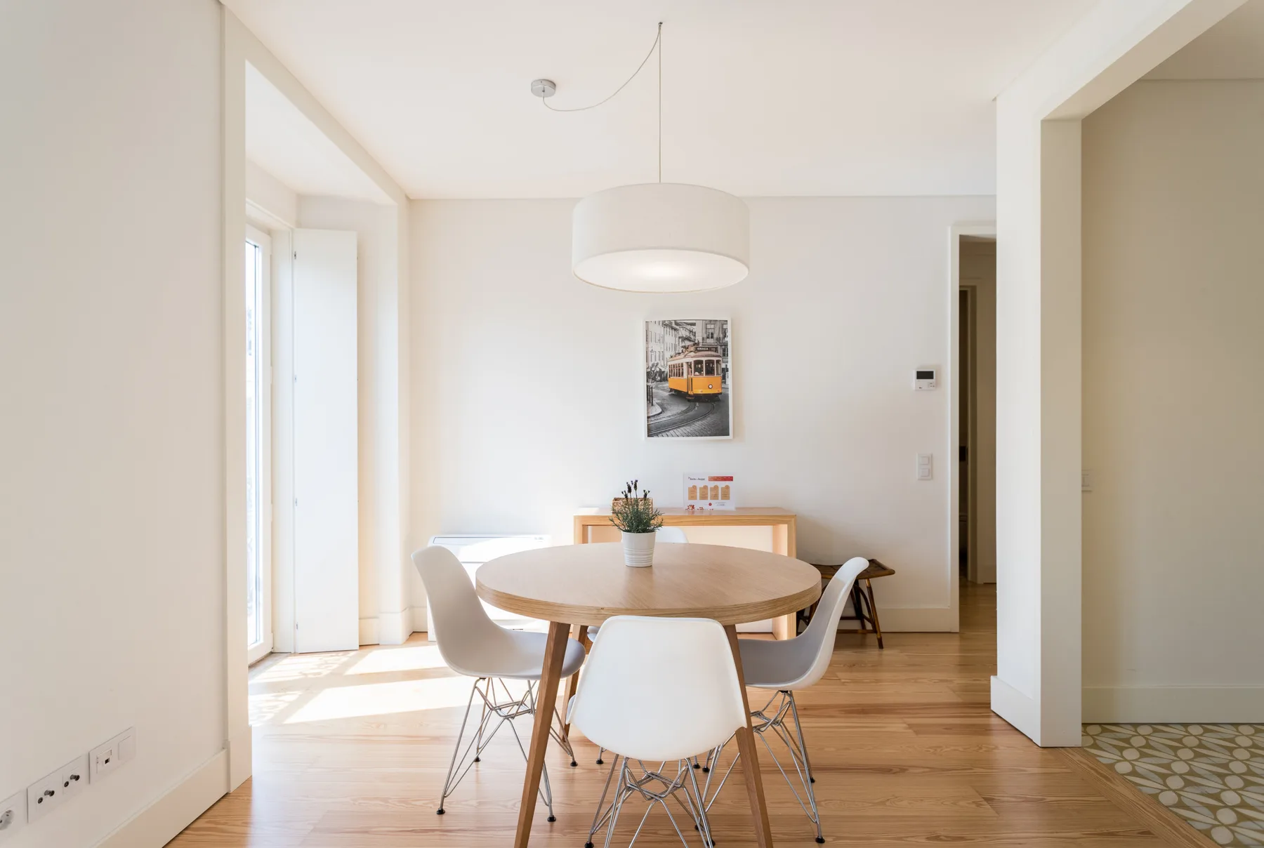 A bright dining area with a round table and chairs beside a large window.