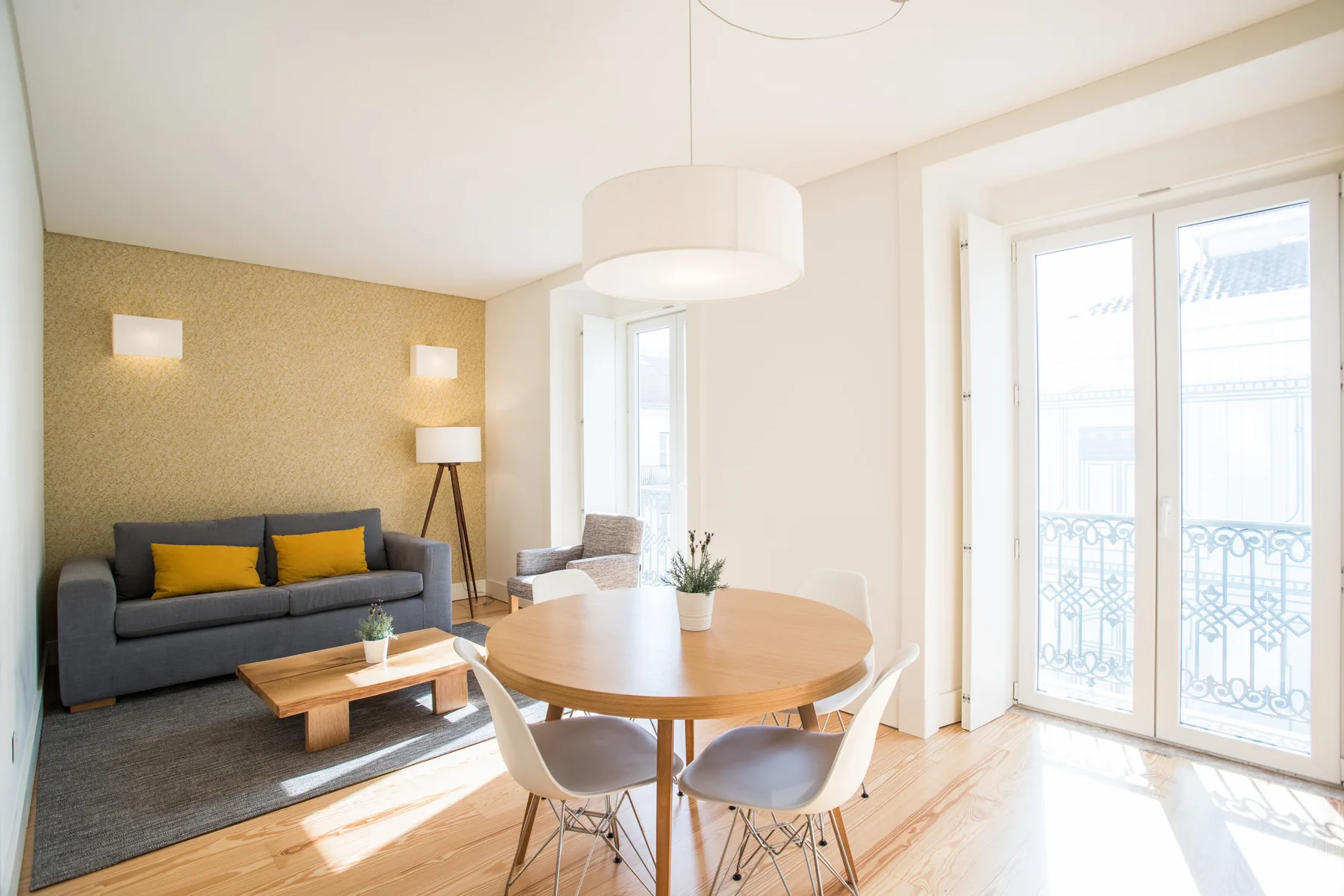 A bright living and dining area with seating, a round table, and balcony doors.