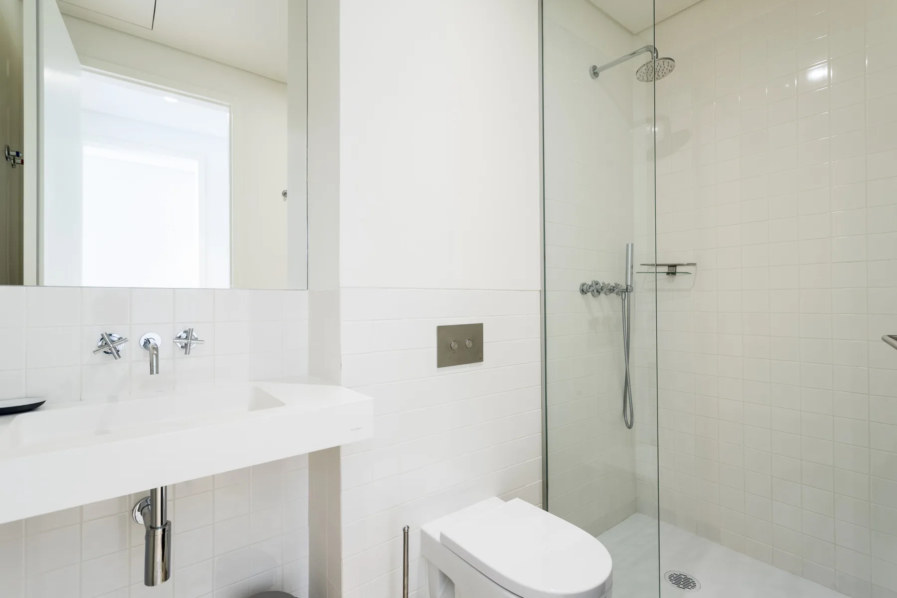 A bright bathroom with a sink, toilet, and shower.