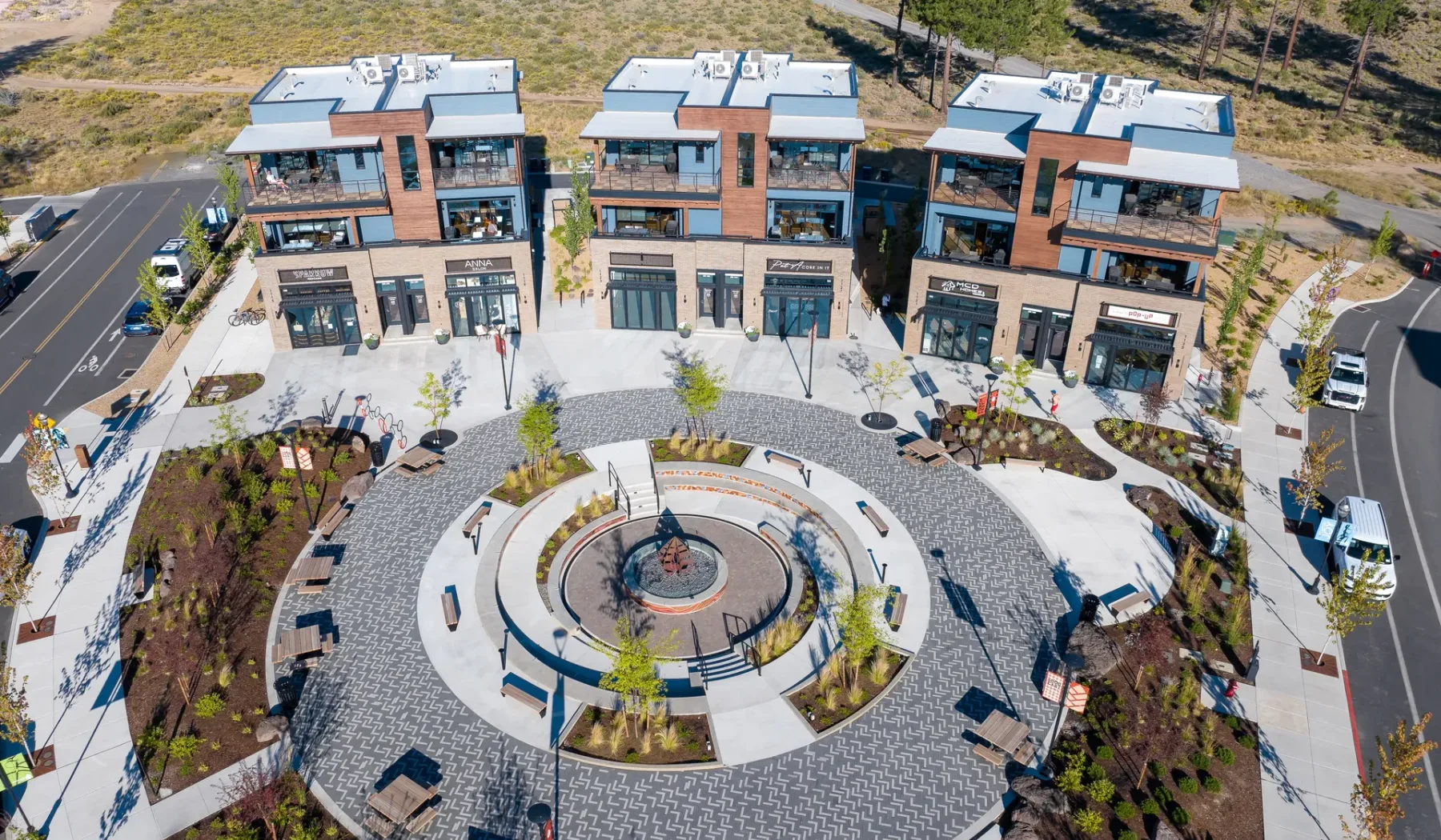 Aerial view of three modern brick buildings surrounding a circular paved plaza.