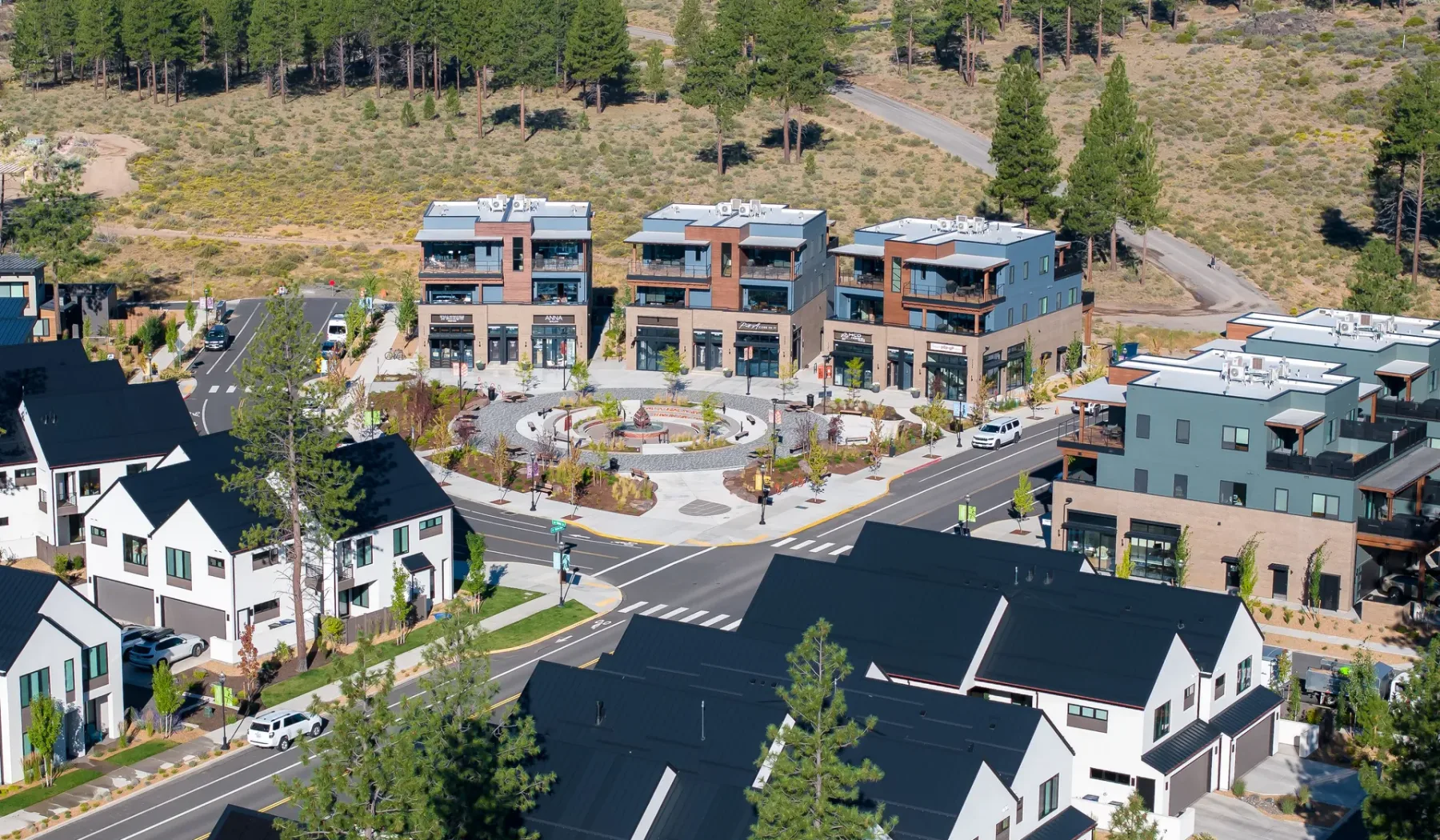 Aerial view of a residential neighborhood with modern buildings and surrounding trees.